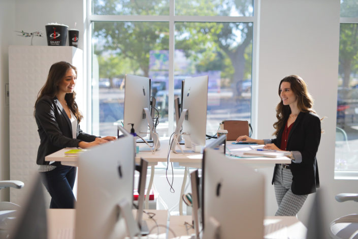 two employees working at standing desks at bright age social media agency