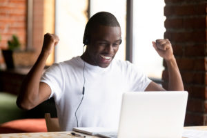 Man is happy about something on the computer to show that contests help your brand