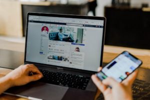 Social media marketing agency shows personal Facebook profile on laptop and phone
