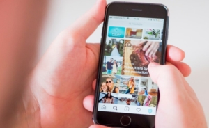 Person scrolling through feed on phone showing social media brand awareness